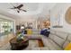 Bright living room with large windows, hardwood floors, stylish sectional, and open floor plan for entertaining at 8715 Se 176Th Lowndes Pl, The Villages, FL 32162
