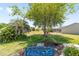 The backyard features mature trees, a blue wrought iron bench and garden, and a meticulously maintained lawn at 929 Eastmont Ct, The Villages, FL 32162