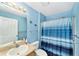 Well-lit bathroom with blue walls, shower with blue striped curtain, and vanity with sink and mirror at 929 Eastmont Ct, The Villages, FL 32162