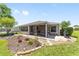 A well-maintained rear exterior of the house shows a screened patio and landscaped yard with stone accents at 929 Eastmont Ct, The Villages, FL 32162