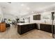 Open concept kitchen showcasing stainless steel appliances, dark cabinetry, and seamless flow to the living room at 947 Couture St, The Villages, FL 32163