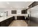 Well-lit kitchen featuring stainless steel appliances, dark cabinets, and a view of the backyard at 947 Couture St, The Villages, FL 32163