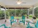 Screened in patio with tiled floor, ceiling fan and seating area with chairs overlooking the lush backyard at 9621 Se 168Th Maplesong Ln, The Villages, FL 32162
