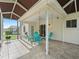 A covered patio with tile flooring, a ceiling fan, and a seating area with comfortable chairs and tables at 9621 Se 168Th Maplesong Ln, The Villages, FL 32162