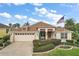 Charming single-Gathering home with a well-manicured lawn, an American flag, and an attached two-car garage at 1606 Mount Croghan Trl, The Villages, FL 32162