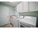 Well-equipped laundry room with modern washer and dryer units and ample storage cabinets at 1606 Mount Croghan Trl, The Villages, FL 32162