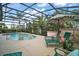 Beautiful in-ground pool within a screened enclosure, complemented by patio furniture and tropical greenery at 1606 Mount Croghan Trl, The Villages, FL 32162
