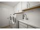 Bright laundry room features white cabinets and appliances, countertop, and a sink at 10282 Julia Isles Ave, Oxford, FL 34484