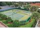 Overhead view of well-maintained tennis and pickleball courts surrounded by lush landscaping and palms at 10282 Julia Isles Ave, Oxford, FL 34484