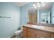 Well-lit bathroom featuring a single vanity with ample storage, a toilet, and a shower with glass doors at 1084 Becker Ave, The Villages, FL 32163