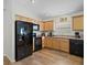 Efficient kitchen with ample wood cabinets, black appliances, and modern lighting fixtures at 1084 Becker Ave, The Villages, FL 32163