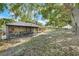 View of the spacious backyard featuring a screened-in porch, mature trees, and a glimpse of a fence at 10851 Lantana Crst, Clermont, FL 34711