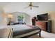 Bedroom with neutral walls, ceiling fan, window view and entertainment center at 10851 Lantana Crst, Clermont, FL 34711