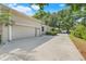 Exterior view of the attached two-car garage with a long driveway and mature landscaping at 10851 Lantana Crst, Clermont, FL 34711