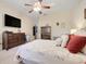 Spacious main bedroom with a ceiling fan, tray ceiling, large dresser with TV, and floral themed bedding at 10851 Lantana Crst, Clermont, FL 34711