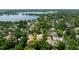 Aerial view of a Mediterranean-style home with a tile roof surrounded by lush greenery near a lake at 1196 Lakeshore Dr, Mount Dora, FL 32757