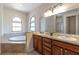 Bright bathroom features double sinks, large mirrors, and a garden tub under arched windows at 1196 Lakeshore Dr, Mount Dora, FL 32757