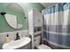 Bathroom with round mirror, vanity, and white cabinet above the toilet, featuring a blue and white striped shower curtain at 12340 Ne 48Th Loop, Oxford, FL 34484