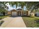 Inviting home exterior featuring a well-maintained lawn, driveway, and a charming front door, showcasing curb appeal at 12340 Ne 48Th Loop, Oxford, FL 34484