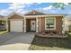 Inviting single-story home with a well-manicured lawn, attached garage, and charming front door wreath at 12340 Ne 48Th Loop, Oxford, FL 34484