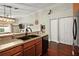Functional kitchen featuring dark countertops, wood cabinets, and stainless steel appliances, connecting to the living area at 12340 Ne 48Th Loop, Oxford, FL 34484