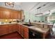 Charming kitchen featuring wood cabinets, dark countertops, and an undermount sink at 12340 Ne 48Th Loop, Oxford, FL 34484