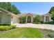 Inviting single-story home featuring a well-manicured lawn, arched entryway, and mature landscaping at 13045 Colonnade Cir, Clermont, FL 34711