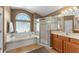 Bright bathroom with a walk-in shower, a soaking tub under a large window, and double sinks at 13045 Colonnade Cir, Clermont, FL 34711