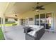 Covered patio featuring a wicker sofa set, ceiling fans, and a view of the spacious backyard at 13045 Colonnade Cir, Clermont, FL 34711