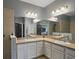 Bright bathroom featuring a double sink vanity, large mirrors, neutral walls, and a tiled walk-in shower at 13328 Lake Yale View Loop, Grand Island, FL 32735