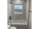 Bathroom featuring marble-look tile, a window, shower with a tub, and modern matte black fixtures at 16487 Sw 55Th, Ocala, FL 34473