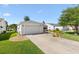 View of home's front exterior with a 1-car garage, tidy landscaping, and mature tree at 17076 Se 96Th Chapelwood Cir, The Villages, FL 32162