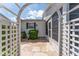 Charming courtyard featuring a white pergola, stone pathway, and well-maintained landscaping at 1709 Betrillo Ct, The Villages, FL 32162