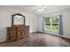 Bedroom with wood floors, ample natural light, and dresser with large mirror at 17238 Se 94Th Coults Cir, The Villages, FL 32162