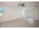 Spacious bedroom with tile floors, a ceiling fan, a bright window, and sliding door access to lanai at 17386 Blazing Star Cir, Clermont, FL 34714