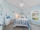 Cozy bedroom with blue walls, white trim, ceiling fan, and a window offering natural light and neighborhood view at 2006 Oppenheimer Ct, The Villages, FL 34762