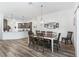 Bright dining room features modern lighting fixture, wall art, and wood-look floors that flow into the kitchen at 2006 Oppenheimer Ct, The Villages, FL 34762