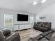 Cozy living room with leather seating, neutral walls, wood-look floors, and ample natural light at 2006 Oppenheimer Ct, The Villages, FL 34762