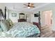 Spacious main bedroom with a tray ceiling, fan, wood-look floors, and a four-poster bed, with ensuite bathroom access at 2006 Oppenheimer Ct, The Villages, FL 34762
