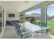 Inviting screened-in patio with ceiling fans, a TV, and a dining table with floral cushioned chairs at 2006 Oppenheimer Ct, The Villages, FL 34762