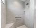 Modern shower featuring gray stone-look tile and convenient grab bar and bench for accessibility at 2006 Oppenheimer Ct, The Villages, FL 34762