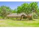 Charming home exterior featuring a well-manicured lawn, mature trees, and a welcoming garden trellis entrance at 2112 Robie Ave, Mount Dora, FL 32757