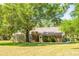 Rear exterior view of the home featuring lush landscaping, a shed, and a brick chimney at 2112 Robie Ave, Mount Dora, FL 32757