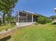 Exterior view of a home with a screened lanai, well-manicured lawn, and a cozy outdoor space at 21707 Queen Mary Ct, Leesburg, FL 34748