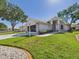 Well-maintained single-story home featuring a manicured lawn, mature trees, and charming landscaping at 21707 Queen Mary Ct, Leesburg, FL 34748