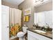Well-lit bathroom with a floral shower curtain, granite countertop, and neutral-colored walls at 26951 White Plains Way, Leesburg, FL 34748