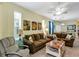 Comfortable living room with brown sofas, tropical artwork, and tile flooring providing a relaxing space at 26951 White Plains Way, Leesburg, FL 34748