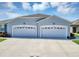 A well-lit two-car garage with white doors that matches the exterior of this lovely building at 27018 White Plains Way, Leesburg, FL 34748