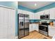 Modern kitchen boasts stainless steel appliances and stylish white cabinets with blue accent wall at 27018 White Plains Way, Leesburg, FL 34748