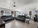 Open-concept living room with two black sofas, ceiling fan, wood floors, and dining area at 2729 Craven Way, The Villages, FL 32162